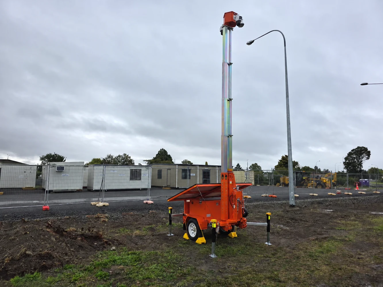 Mobile equipment with a raised mast on an outdoor worksite